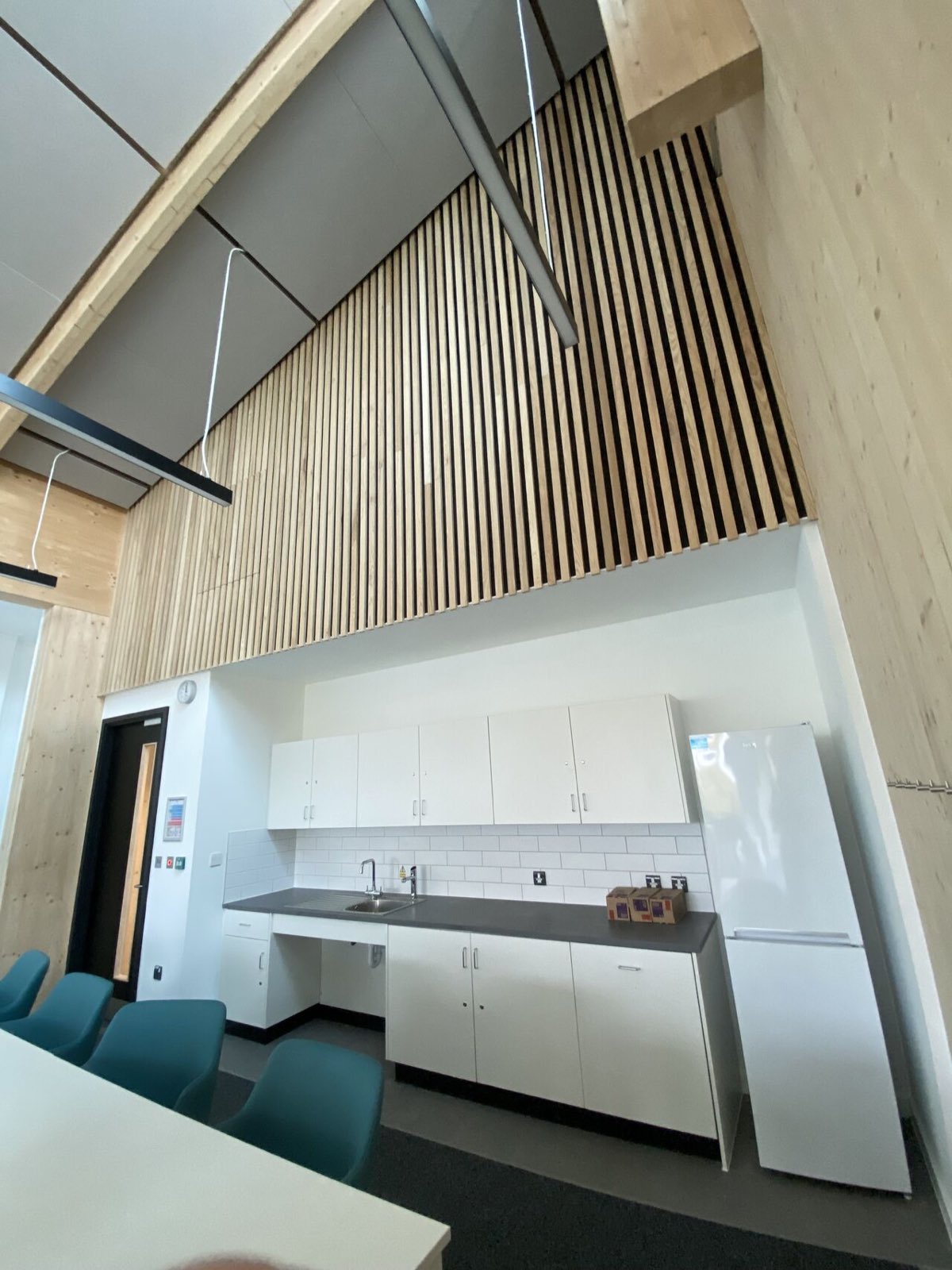 Completed interior — timber slat acoustic wall lining and suspended ceiling to a double-height break-out space
