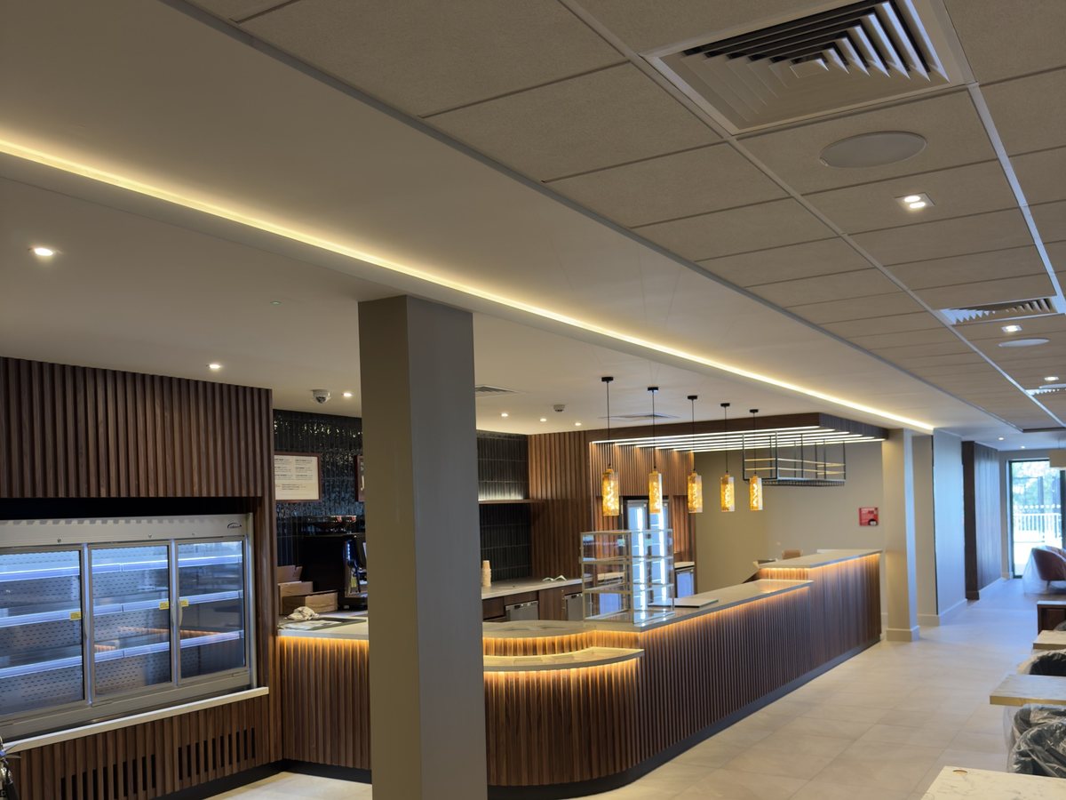 Exposed grid ceiling with a cove-lit plasterboard bulkhead over a club café